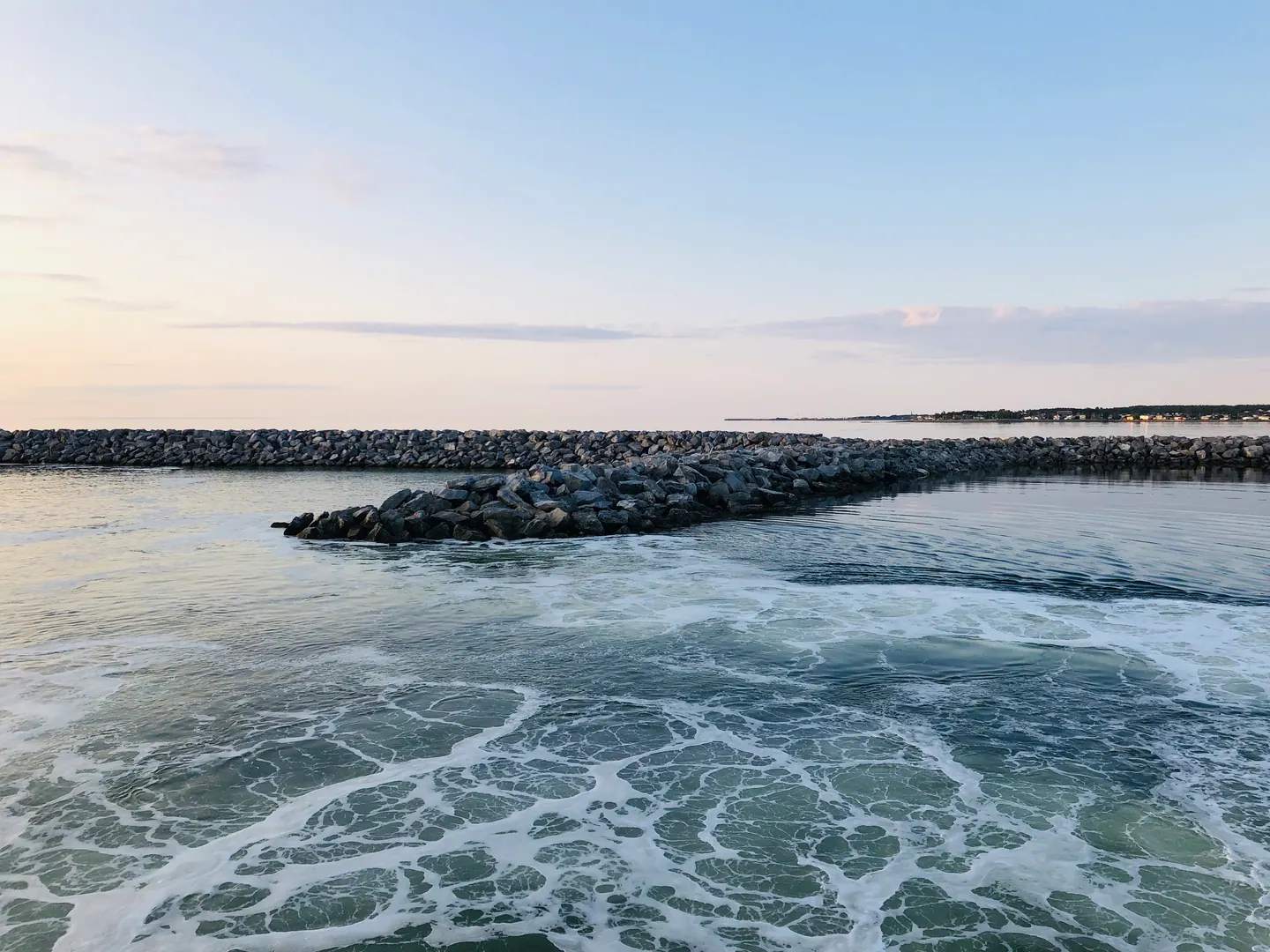 Vagues écumantes contre un brise-lames de pierres, au crépuscule